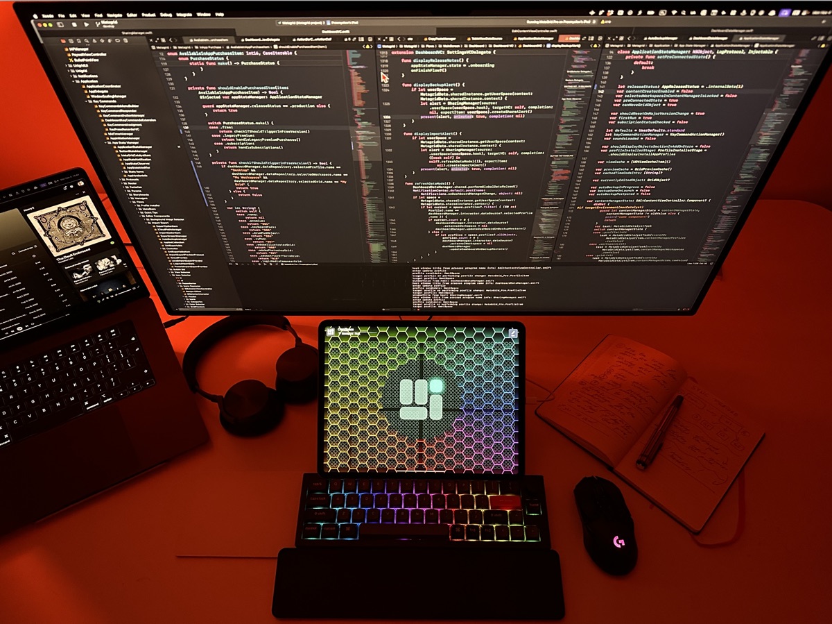 Przemek's complete workspace — monitor with Xcode, iPad with MetaGrid Pro, RGB keyboard, headphones, and mouse